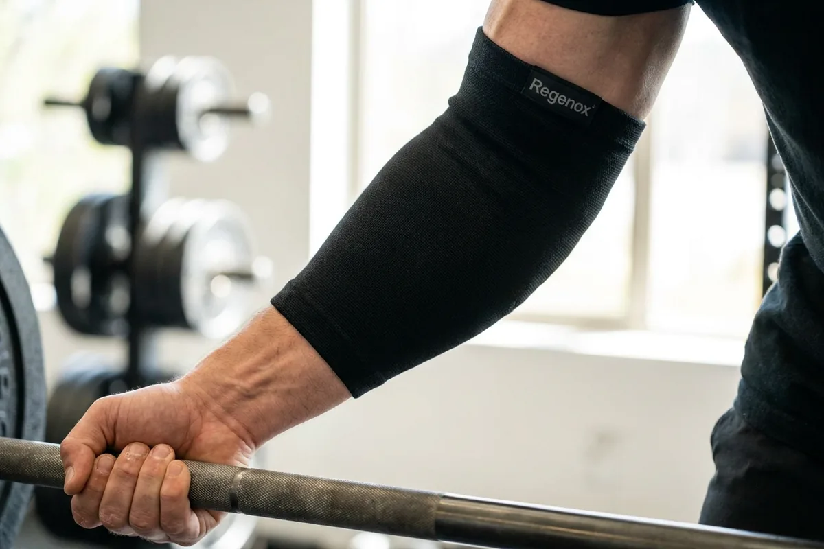 Arm gripping a barbell wearing a black Regenox elbow sleeve