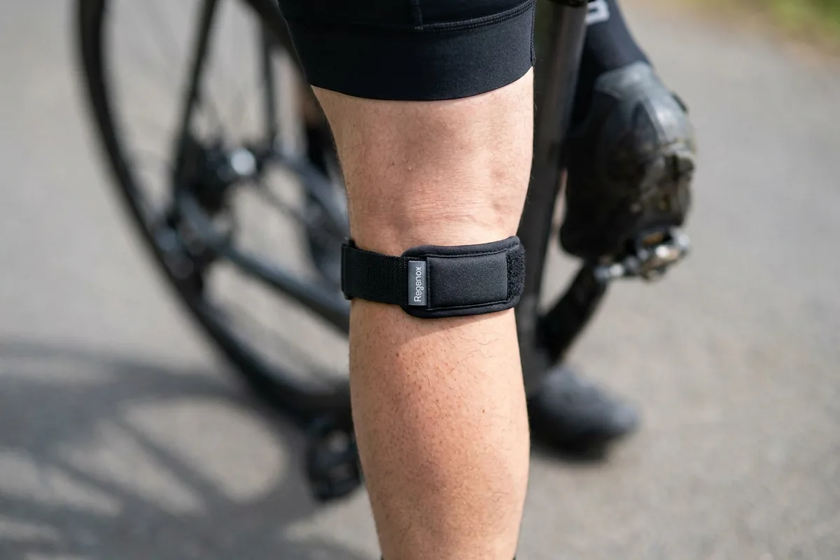 Cyclist's leg wearing a black Regenox patella strap below the kneecap